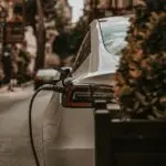 White electric car charging on an urban city street, emphasizing eco-friendly transportation.