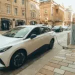 White electric car charging at a modern station on a Glasgow street.