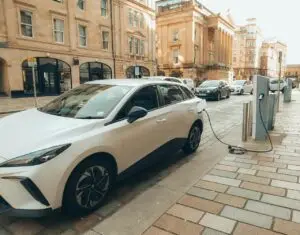 White electric car charging at a modern station on a Glasgow street.