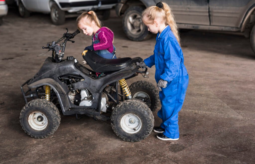 deux petites filles en combinaison inspectant un velo