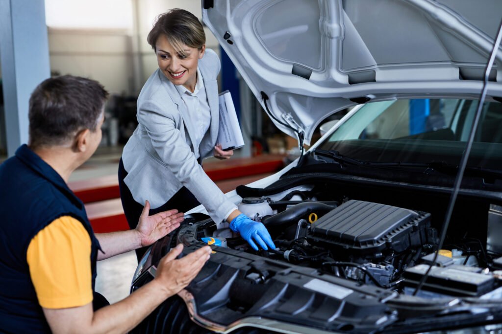 mecanicien automobile et femme d affaires cooperant lors de la verification sous le capot du vehicule dans un atelier