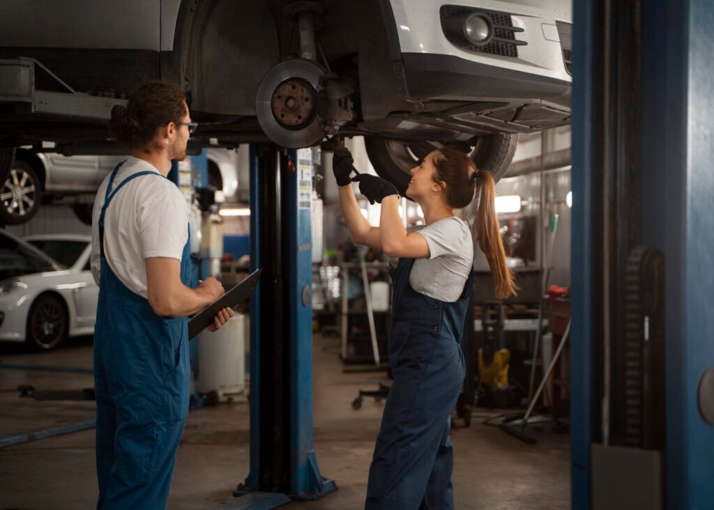 mecaniciens masculins et feminins travaillant dans le magasin sur une voiture 2