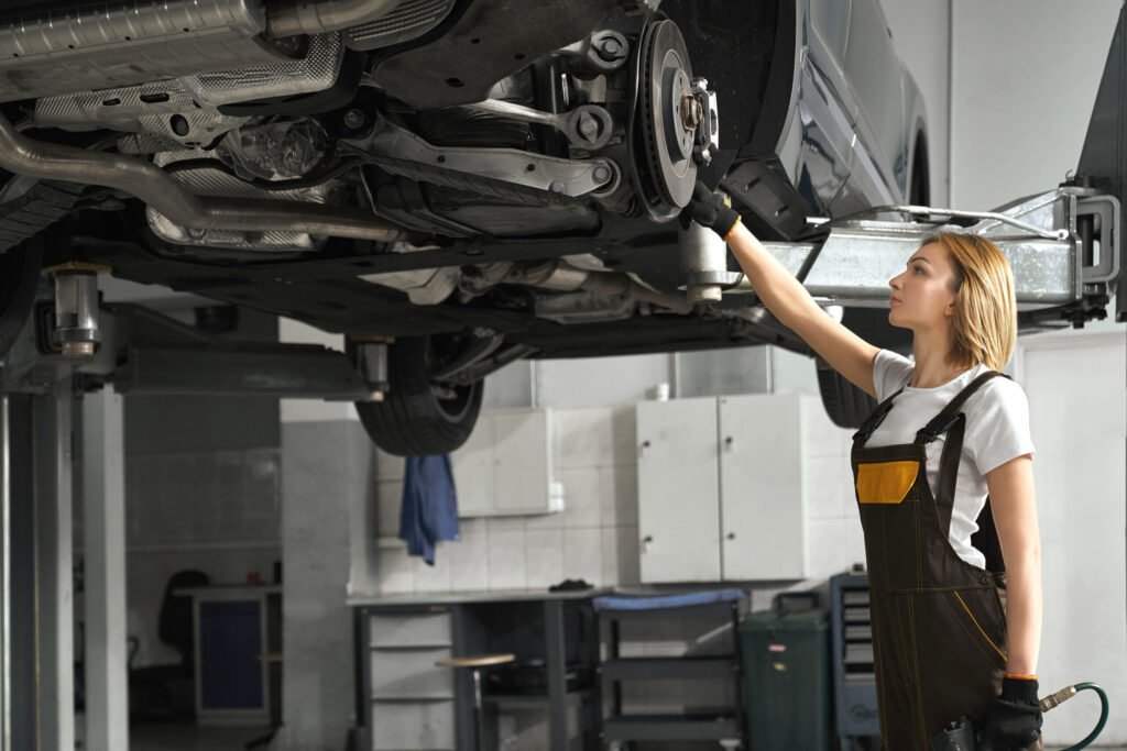 femme en combinaison fixant les disques de frein de la voiture levee